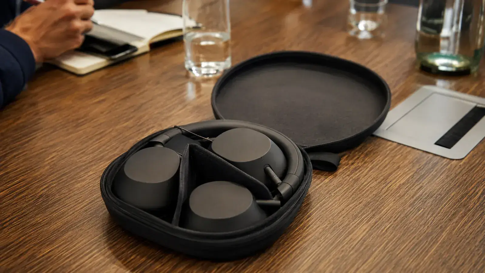 Sony WH-1000XM5 carry case open showing headphones stored inside on a conference table